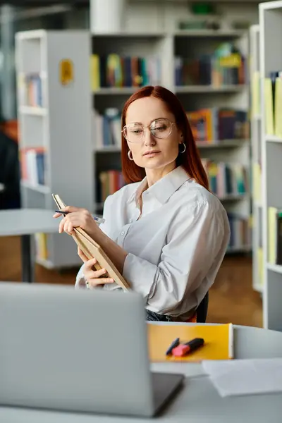 A redheaded female tutor teaches online from a library, using a laptop for after-school lessons. — Stock Photo