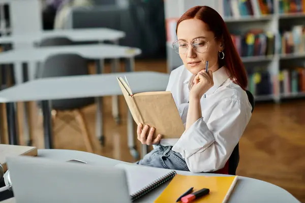 A redhead woman immersed in a book, surrounded by shelves of books in a library, engrossed in quiet study. — Stock Photo