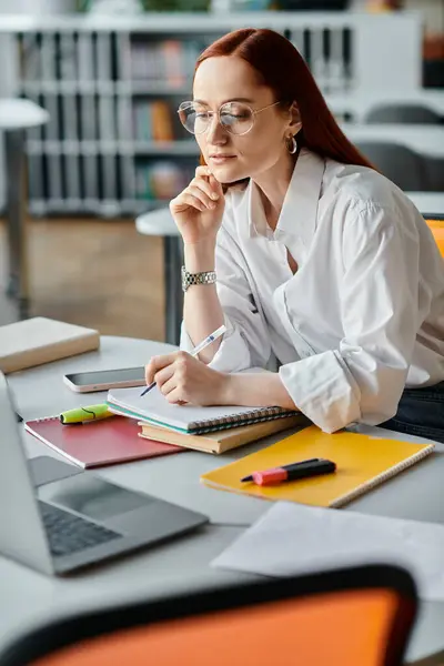 Una tutor dai capelli rossi si siede a una scrivania, insegnando online con un computer portatile dopo una lezione scolastica. — Foto stock
