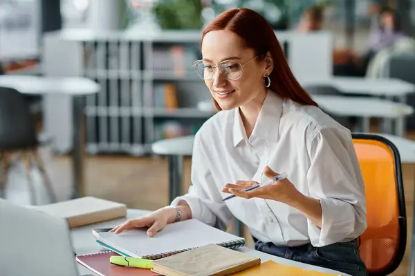 Un tutor donna dai capelli rossi impegnato in una sessione di insegnamento online durante l'utilizzo di un computer portatile per lezioni post-scolastiche. — Foto stock