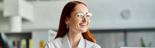 Eine rothaarige Lehrerin mit Brille lächelt, während sie nach einer Schulstunde online unterrichtet. — Stockfoto
