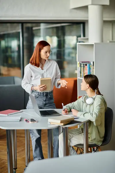 A redhead woman teaches a teenage girl at a table in an office, using a laptop for modern education after school. — Stock Photo