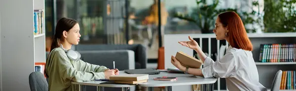 A redhead woman tutors a teenage girl at a table in a library, using a laptop for after-school lessons and modern education. — Stock Photo