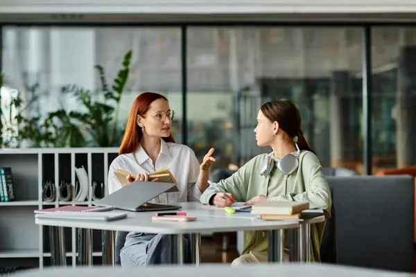 A redhead woman tutors a teenage girl, both engrossed in after-school lessons — Stock Photo