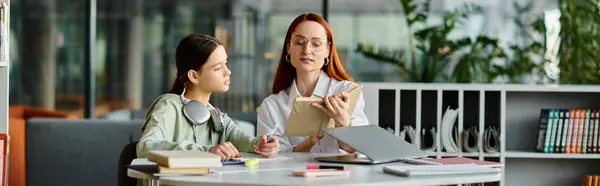 Femme rousse tuteurs sa fille adolescente, tous deux concentrés sur un ordinateur portable pendant les cours après l'école dans un cadre de bureau moderne. — Photo de stock