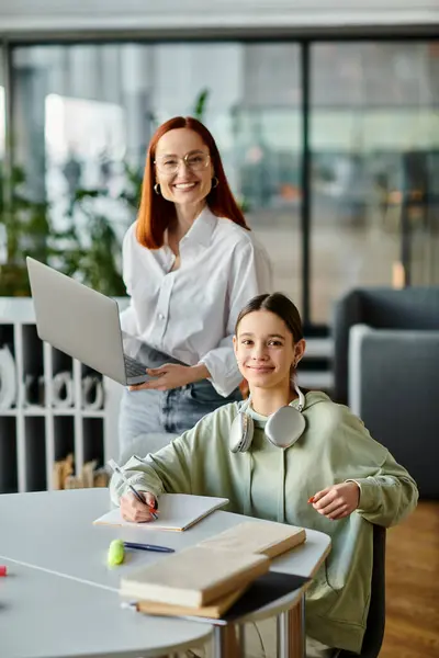 Una rossa sta insegnando a una ragazza adolescente in un ambiente di ufficio, utilizzando un computer portatile per lezioni post-scolastiche.. — Foto stock