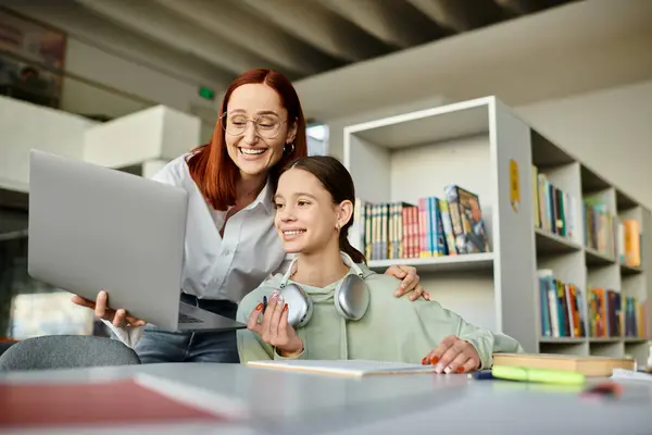 Rossa tutor donna adolescente ragazza sul computer portatile in biblioteca, impegnandosi in una moderna educazione post-scuola. — Foto stock