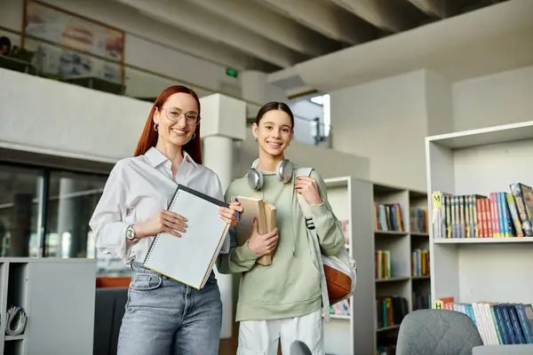 A tutor and her student, engage in after-school lessons in a library, with a folder in hand for study materials. — Stock Photo