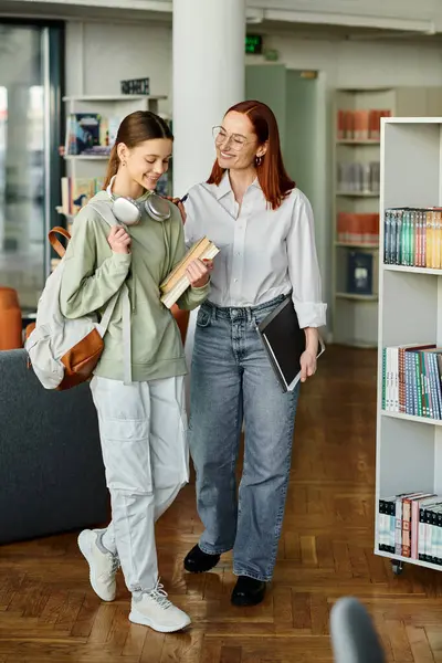 Sessione di tutoraggio tra una rossa e un'adolescente in una biblioteca, impegnata in una conversazione profonda — Foto stock