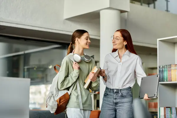 A redhead tutor and a teenage student - engage in deep conversation in a library, surrounded by books. — Stock Photo