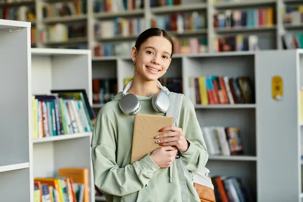 Дівчина занурена в книгу і насолоджується музикою в бібліотечному середовищі. — стокове фото