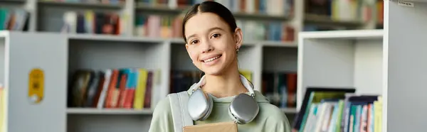 Дівчина-підліток з книгою в бібліотеці, сучасна освіта. — стокове фото