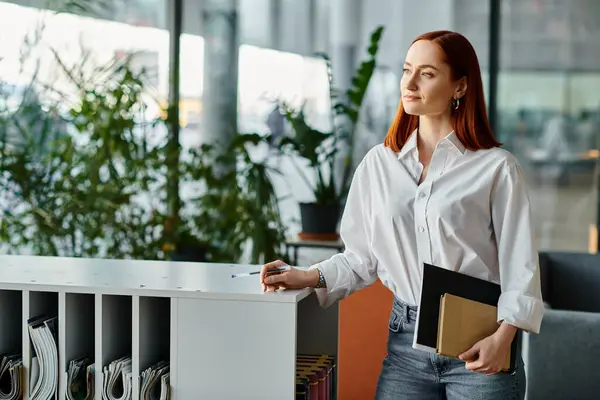 Redhead woman stands with notebook and book, modern education scene. — Stock Photo