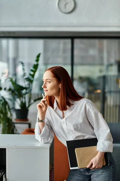 Tutor rossa in camicia bianca appoggiato a una scrivania, sessione doposcuola. — Foto stock