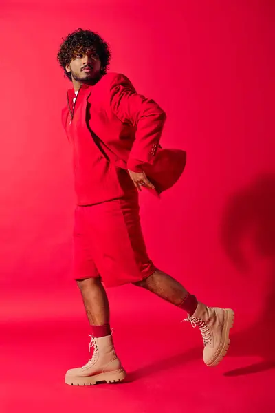 Schöner indischer Mann in rotem Kapuzenpulli posiert vor einer lebendigen Kulisse. — Stockfoto