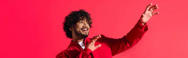 A handsome young Indian man in a vibrant red jacket strikes a dramatic gesture. — Stock Photo