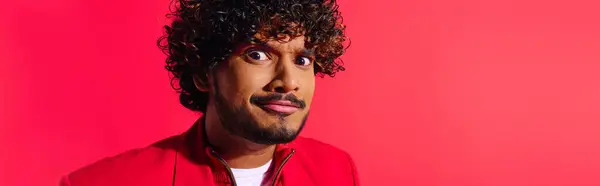 Um belo jovem indiano com cabelo encaracolado posando em uma jaqueta vermelha vibrante. — Fotografia de Stock