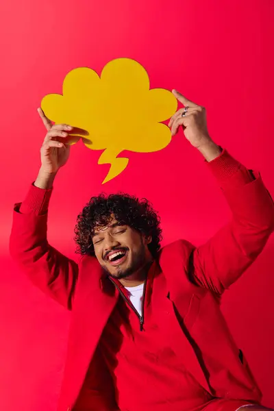 Handsome Indian man in colorful outfit holding speech bubble overhead. — Stock Photo