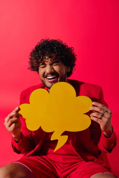 Handsome Indian man in red shirt poses with speech bubble on vibrant backdrop. — Stock Photo