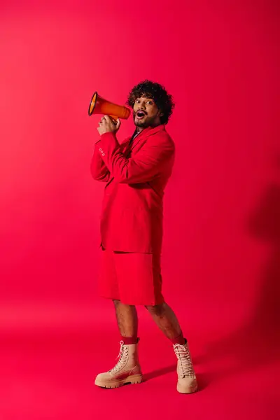Un giovane indiano in un abito rosso vibrante con un megafono rosso. — Foto stock