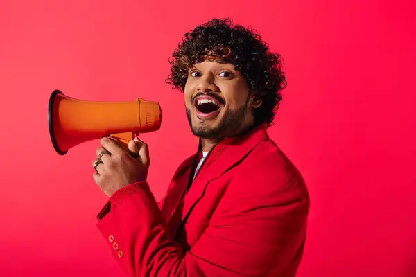 Um jovem indiano com um casaco vermelho tem um megafone vermelho e laranja. — Fotografia de Stock