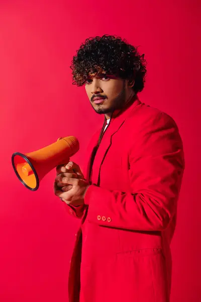 Giovane uomo indiano in abito rosso in possesso di megafono rosso e giallo. — Foto stock