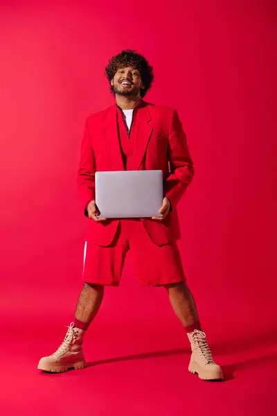 Handsome young Indian man in red suit poses with laptop. — Stock Photo