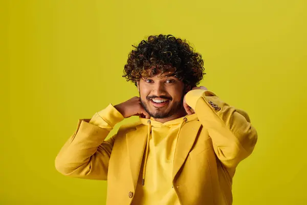 Bonito jovem indiano em uma jaqueta amarela sorrindo em um cenário vibrante. — Fotografia de Stock