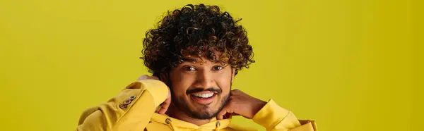Красивий індійський чоловік з кучерявим волоссям позує в стильній жовтій сорочці на яскравому тлі. — стокове фото