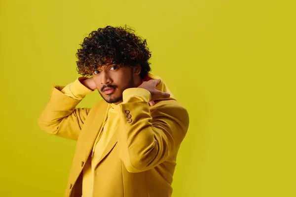 Bonito jovem indiano com uma jaqueta amarela segurando as mãos em seus ouvidos. — Fotografia de Stock