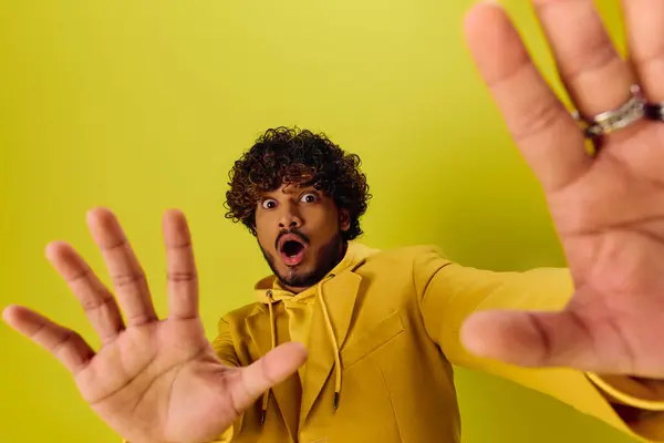 A handsome young Indian man in a yellow hoodie is making a gesture. — Stock Photo