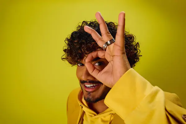 A handsome young Indian man in a vibrant outfit making a OK sign with his fingers. — Stock Photo