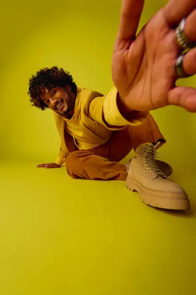 A man in vibrant attire sits against a bright yellow background. — Stock Photo