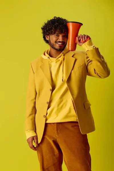 Beau Indien en veste jaune pose avec un mégaphone rouge. — Photo de stock