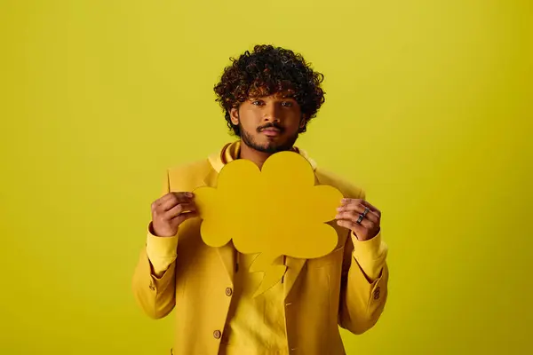 Красивий молодий індійський чоловік у жовтому костюмі, що тримає бульбашку мовлення. — стокове фото