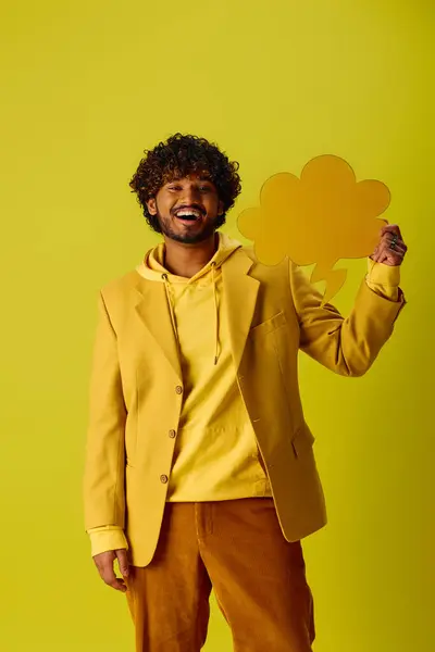 Handsome young Indian man in vibrant yellow jacket and brown pants posing against vivid backdrop. — Stock Photo