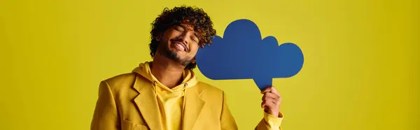 Handsome young Indian man in yellow jacket holding speech bubble. — Stock Photo