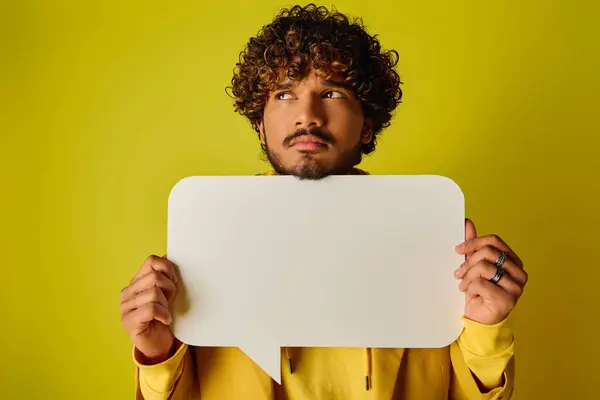 Ein Mann mit lockigem Haar hält eine weiße Sprechblase. — Stockfoto