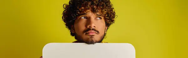 A man with curly hair holds a speech bubble. — Stock Photo
