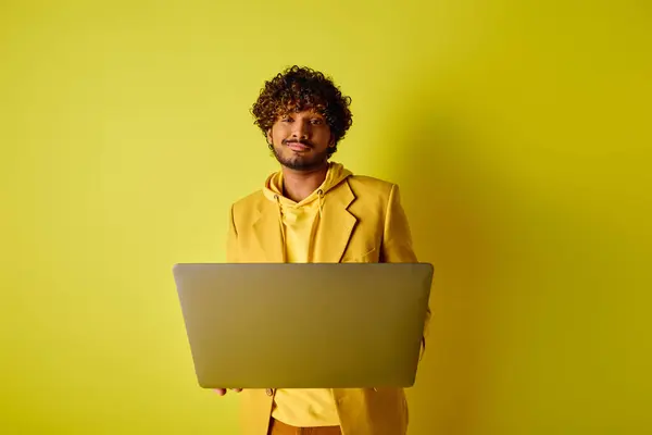 Handsome Indian man in yellow suit poses with laptop. — Stock Photo