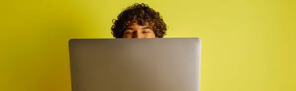 Un hombre con un traje indio vibrante se sienta concentrado frente a una computadora portátil. - foto de stock