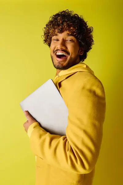 Handsome man with curly hair holding a laptop. — Stock Photo