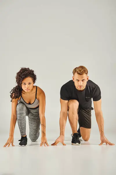 Un jeune couple sportif interracial portant une tenue active démontrant une forme de squat parfaite à l'unisson sur fond blanc. — Photo de stock