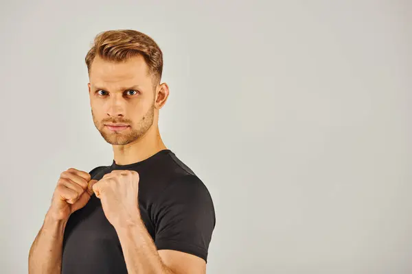 A young athletic man in active wear confidently poses with his fists clenched, exuding strength and determination. — Stock Photo