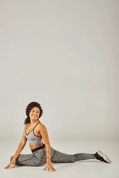 Молодая афроамериканка в активной одежде изящно выполняет позу йоги на белом фоне.. — стоковое фото