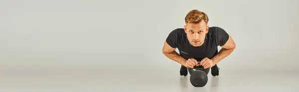 A man in a black shirt gracefully performing a squat on a white background in a studio, showcasing strength and flexibility. — Stock Photo