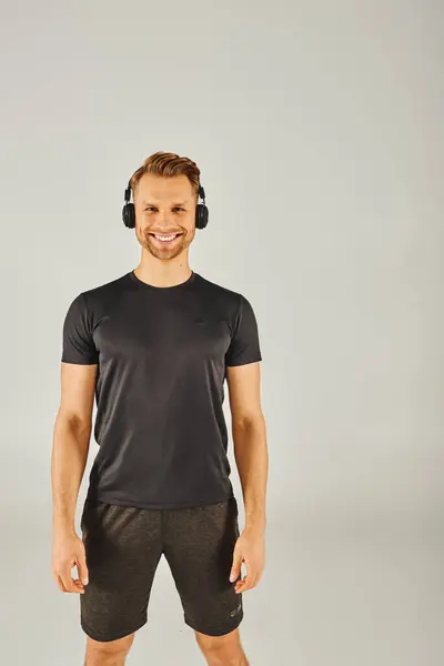 Un jeune sportif en tenue active est absorbé par la musique, portant un casque et un t-shirt, plongé dans sa routine d'entraînement. — Photo de stock