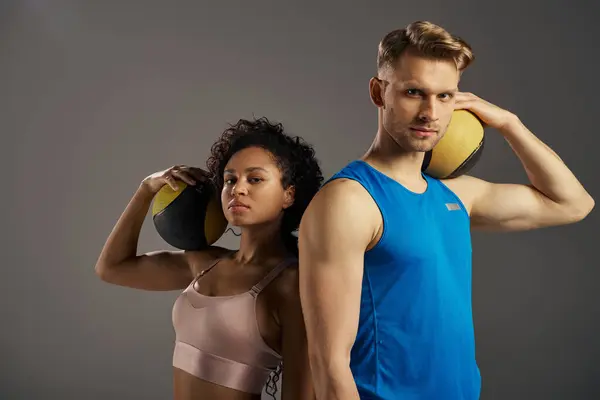 Young multicultural couple in active wear pose with balls in studio setting. — Stock Photo