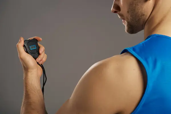 A man in a blue tank top is seen holding an electronic timer. — Stock Photo