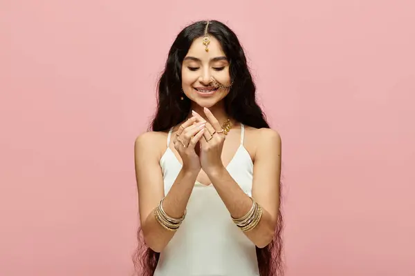 Mujer india joven rezando frente a un vibrante telón de fondo rosa. - foto de stock